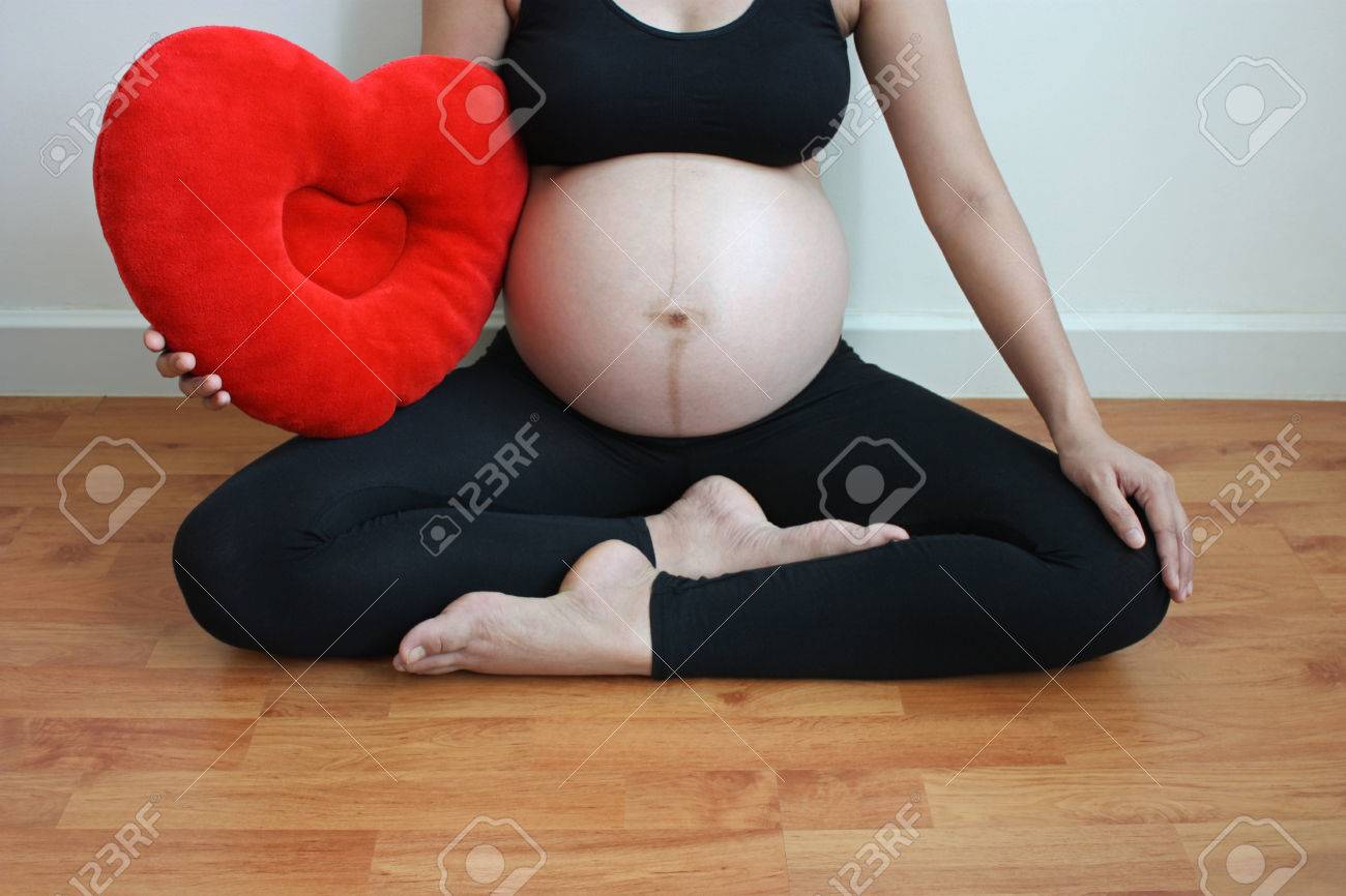 赤いハートの枕と 8 ヶ月のアジアの女性妊娠中大きなお腹 の写真素材 画像素材 Image