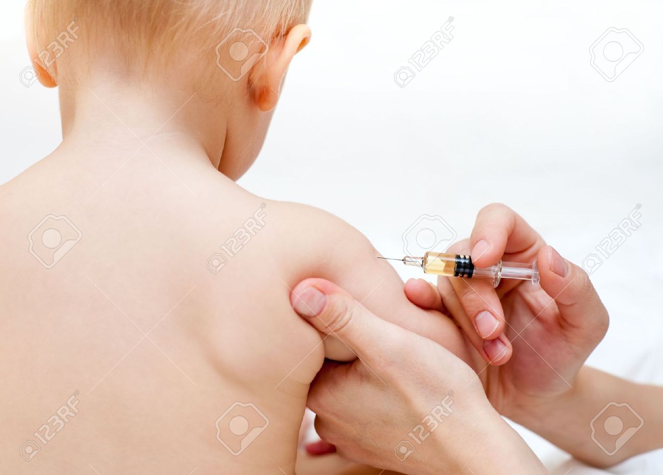 doctor giving a child an intramuscular injection in arm stock photo