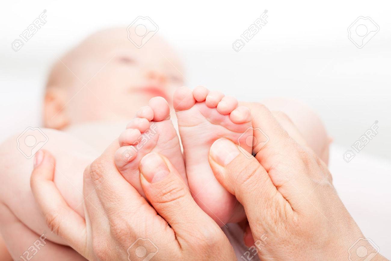 Close-up shot of three month baby girl receiving foot massage from a female massage therapist. Camera is focused on infant's feet. Face is blurred in background. - 39023272 Close-up shot of three month baby girl receiving foot massage from a female massage therapist. Camera is focused on infant's feet. Face is blurred in background. - 39023272