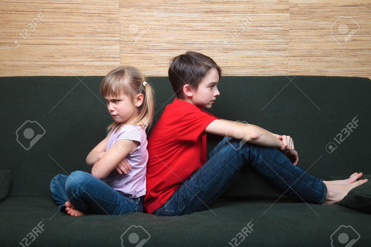 Brother and sister wearing casual clothes sitting on a green sofa back to back sad and frown - 51237240 Brother and sister wearing casual clothes sitting on a green sofa back to back sad and frown - 51237240