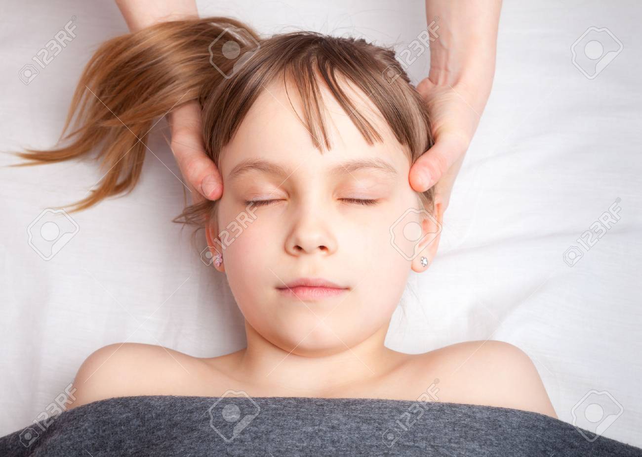 Elementary age girl's head being manipulated by an osteopath - an alternative medicine treatment - 78926226 Elementary age girl's head being manipulated by an osteopath - an alternative medicine treatment - 78926226