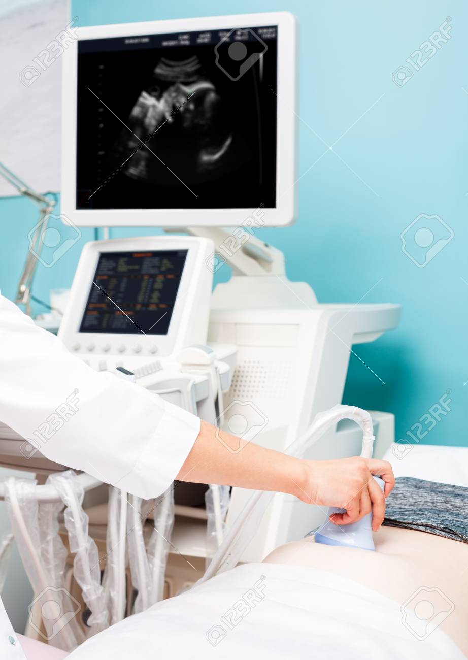 Sonographer scanning young pregnant woman's belly with ultrasonic transducer doing obstetric ultrasonography - 89044162 Sonographer scanning young pregnant woman's belly with ultrasonic transducer doing obstetric ultrasonography - 89044162