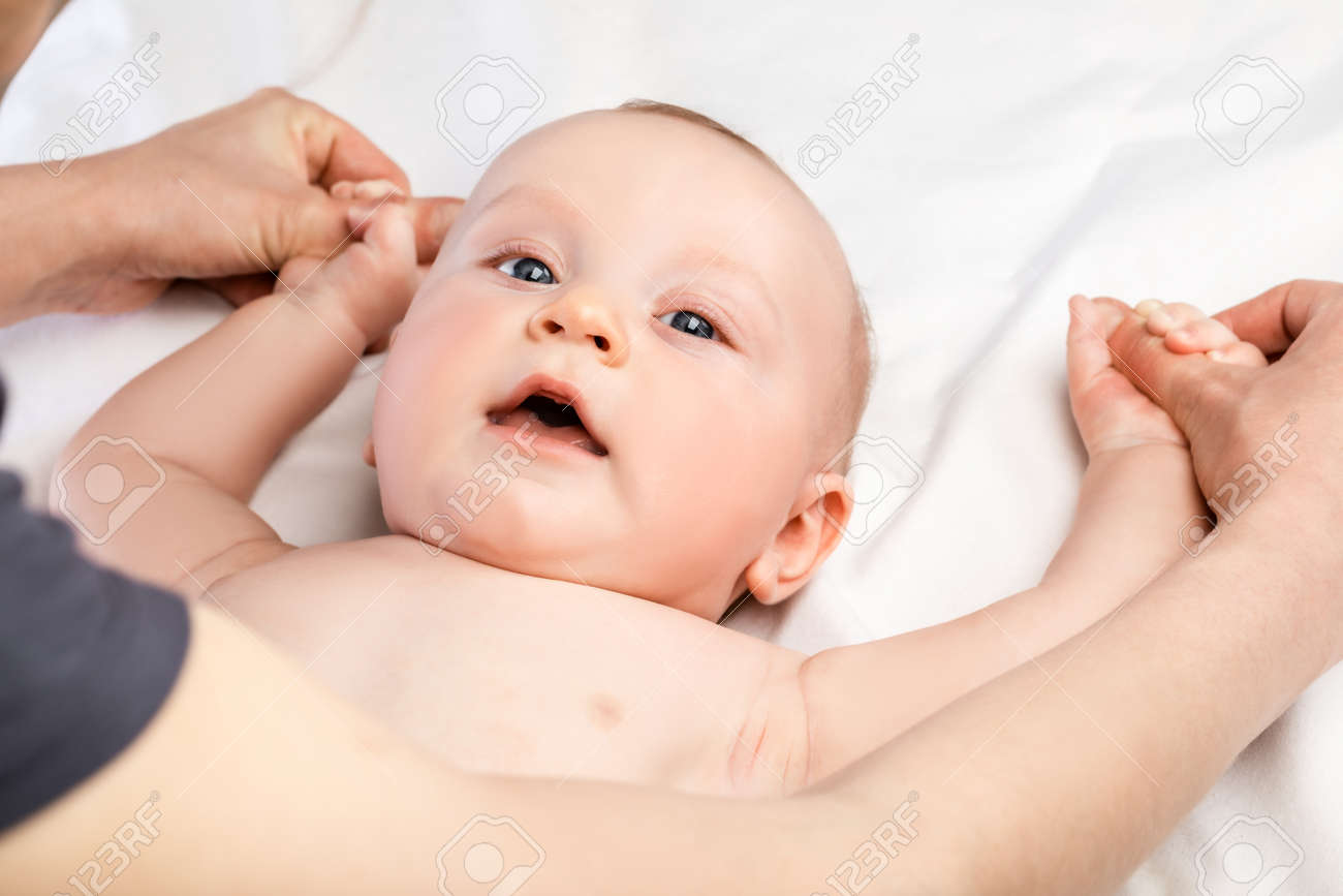 FIve month baby boy receiving massage therapy at home during pandemic quarantine. Massage therapist manipulating child's arms - 165290961 FIve month baby boy receiving massage therapy at home during pandemic quarantine. Massage therapist manipulating child's arms - 165290961