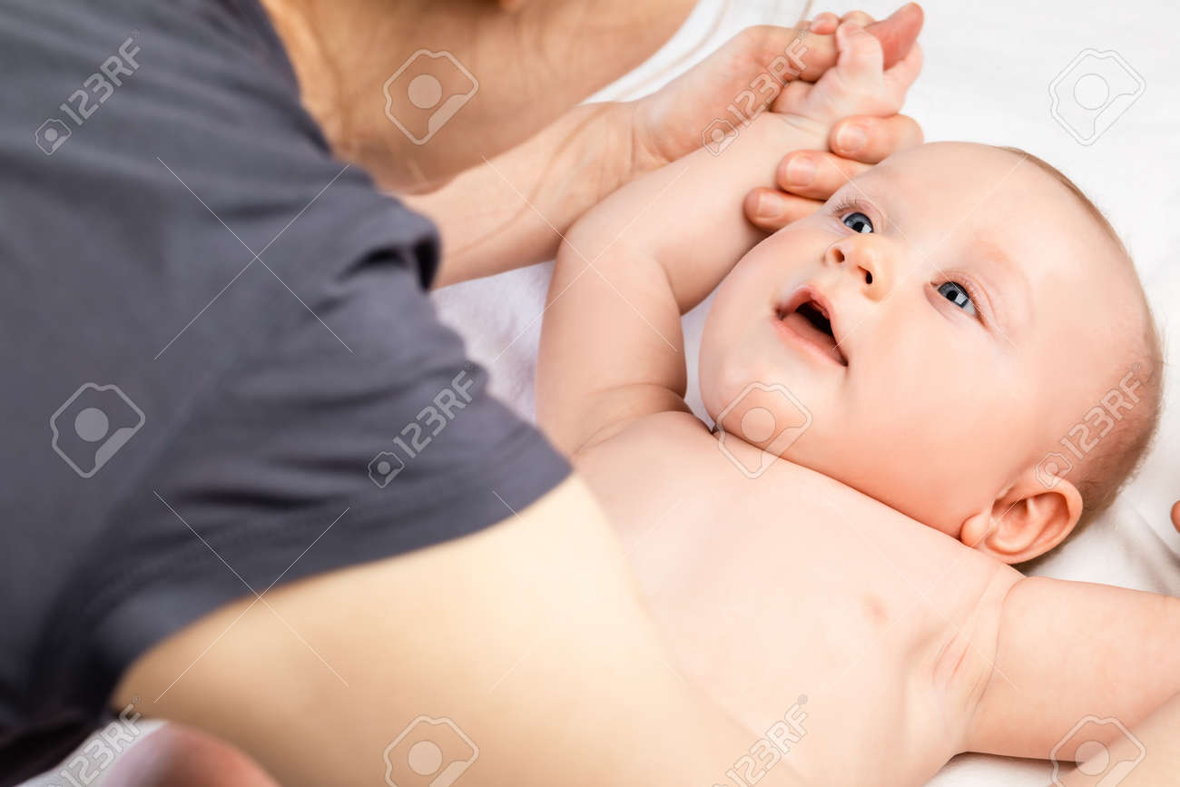 FIve month baby boy receiving massage therapy at home during pandemic quarantine. Massage therapist manipulating child's arms - 165290976 FIve month baby boy receiving massage therapy at home during pandemic quarantine. Massage therapist manipulating child's arms - 165290976