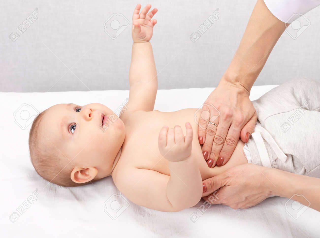 Female pediatrician or health care practitioner examines baby girl's abdomen. Doctor performing manual palpation. Child physical examination concept - 166892506 Female pediatrician or health care practitioner examines baby girl's abdomen. Doctor performing manual palpation. Child physical examination concept - 166892506