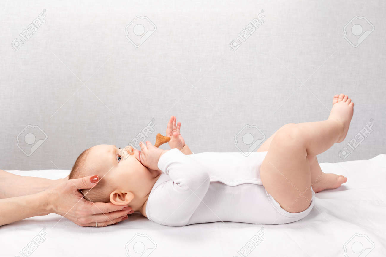 Six month baby girl receiving osteopathic or chiropractic treatment in pediatric clinic. Manual therapist manipulates child's head and neck - 166892234 Six month baby girl receiving osteopathic or chiropractic treatment in pediatric clinic. Manual therapist manipulates child's head and neck - 166892234