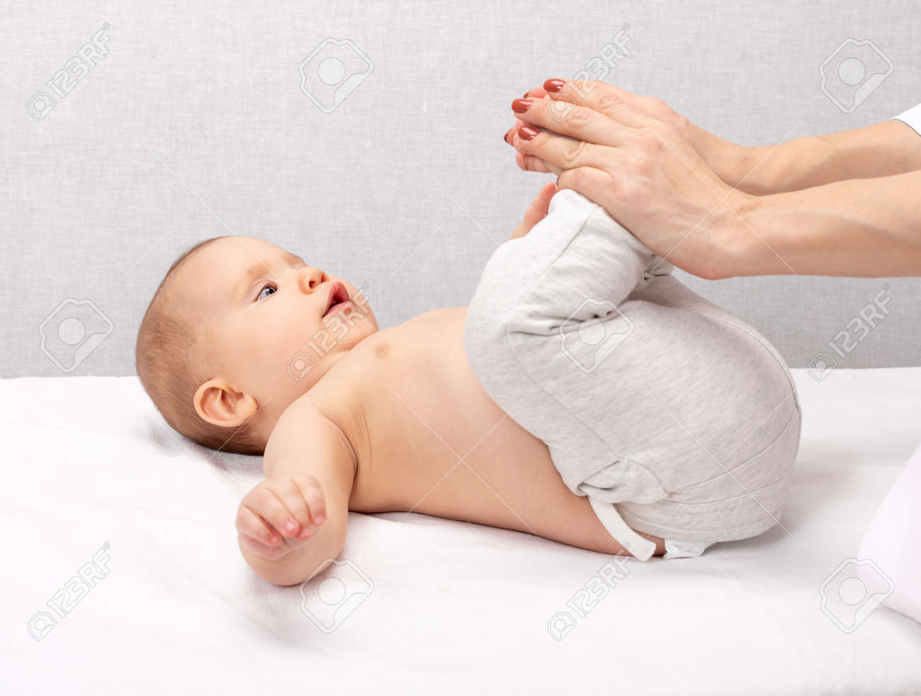 Six month baby girl receiving osteopathic or chiropractic treatment in pediatric clinic. Manual therapist manipulates child's legs and hips - 166892407 Six month baby girl receiving osteopathic or chiropractic treatment in pediatric clinic. Manual therapist manipulates child's legs and hips - 166892407