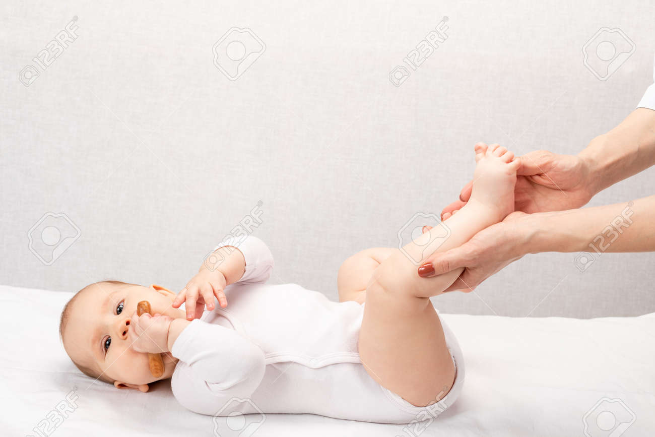 Happy six month baby girl receiving massage therapy in pediatric clinic. Manual therapist manipulates child's foot - 166892861 Happy six month baby girl receiving massage therapy in pediatric clinic. Manual therapist manipulates child's foot - 166892861