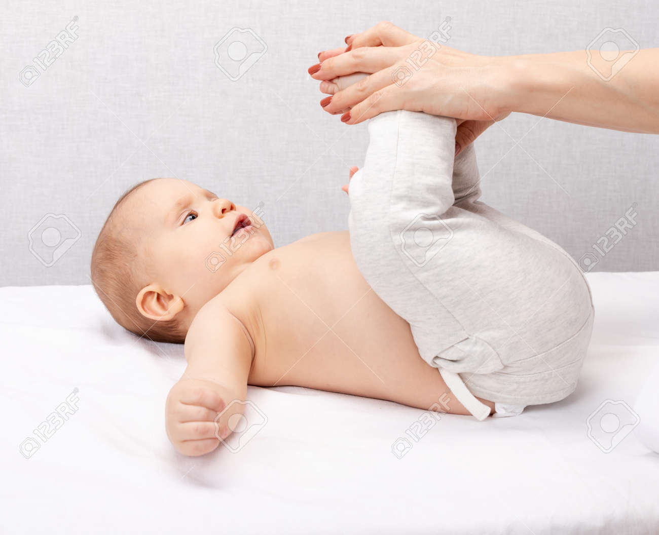 Physiotherapist performing development exercise with six month baby girl in pediatric clinic. Doctor manipulates child's legs to increase flexibility of ankles, hips and knees - 166933714 Physiotherapist performing development exercise with six month baby girl in pediatric clinic. Doctor manipulates child's legs to increase flexibility of ankles, hips and knees - 166933714