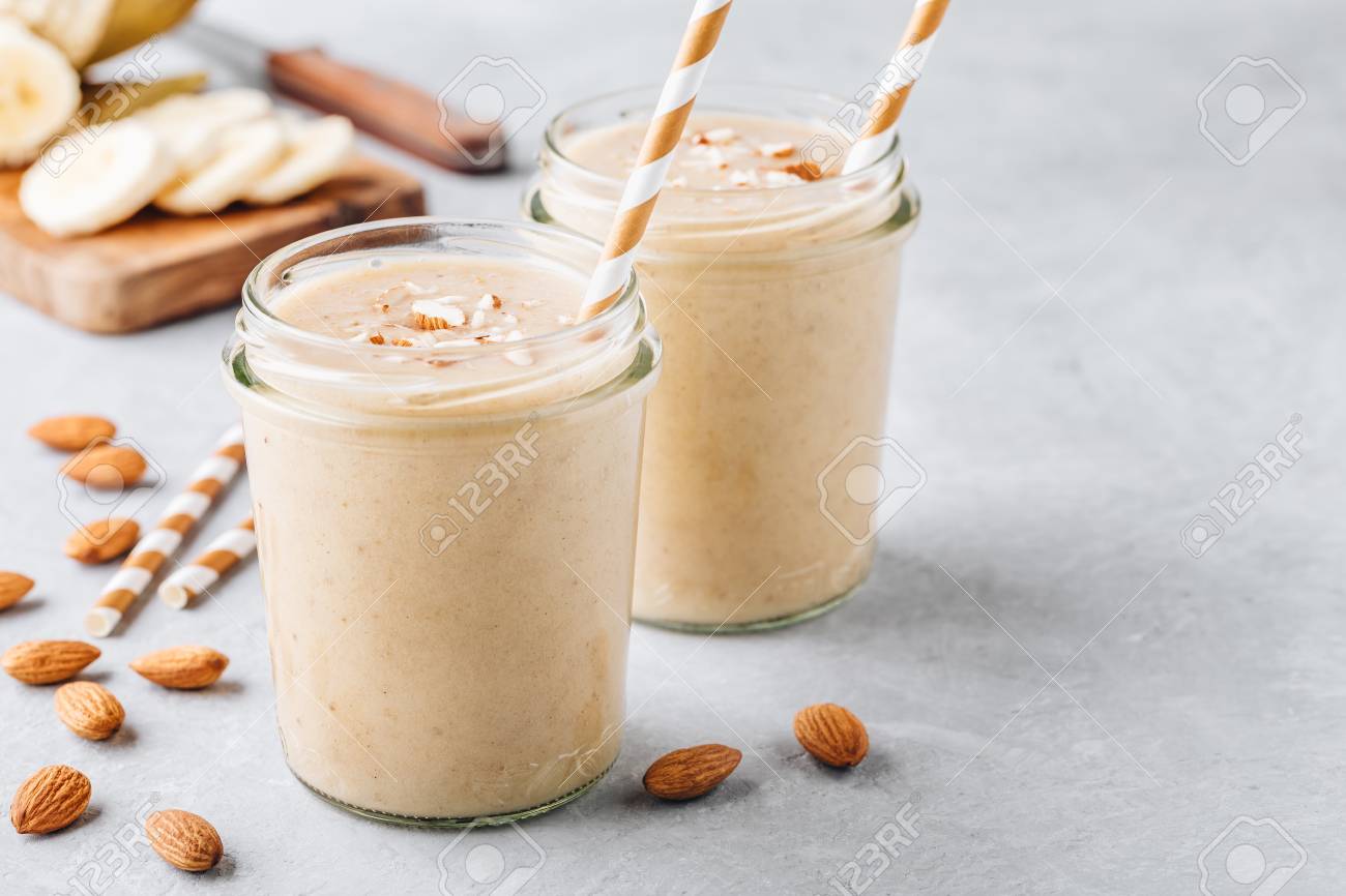 Healthy breakfast. Banana almond smoothie with cinnamon and oat flakes and coconut milk in glass jars - 105757449 Healthy breakfast. Banana almond smoothie with cinnamon and oat flakes and coconut milk in glass jars - 105757449