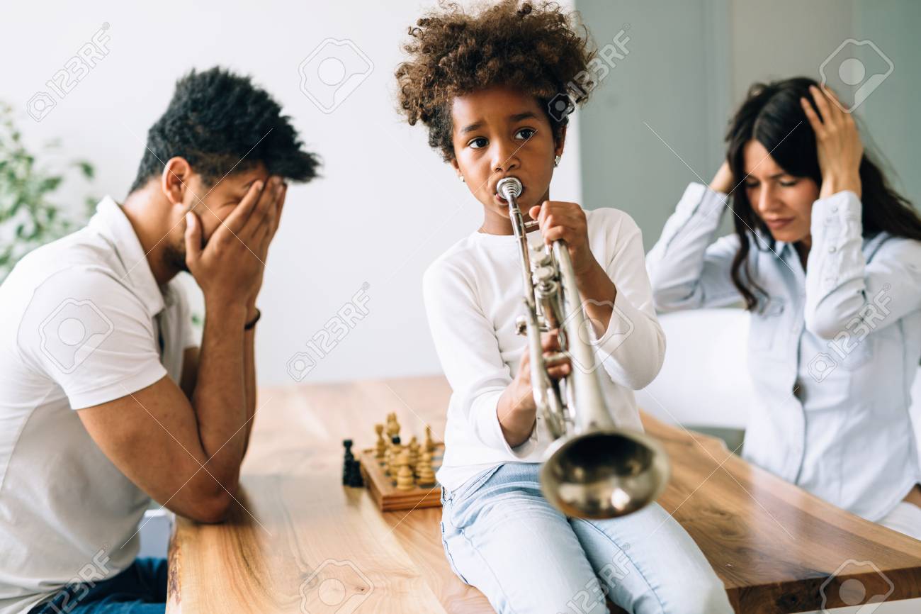 Picture of child making noise by playing trumpet in front of parents - 82268014 Picture of child making noise by playing trumpet in front of parents - 82268014