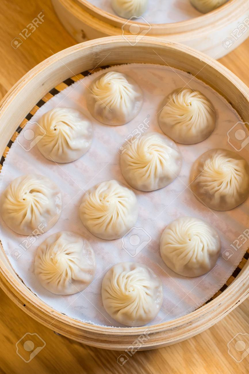 chinese steamed bun in bamboo steamer on wooden table stock photo