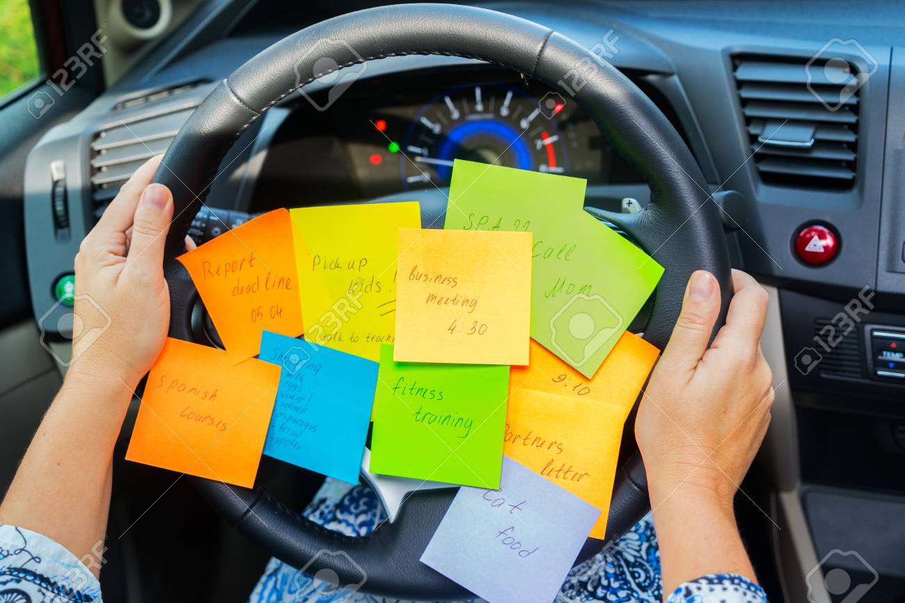 Two hands holding driving wheel and to do list in a car - busy day concept - 103215554 Two hands holding driving wheel and to do list in a car - busy day concept - 103215554