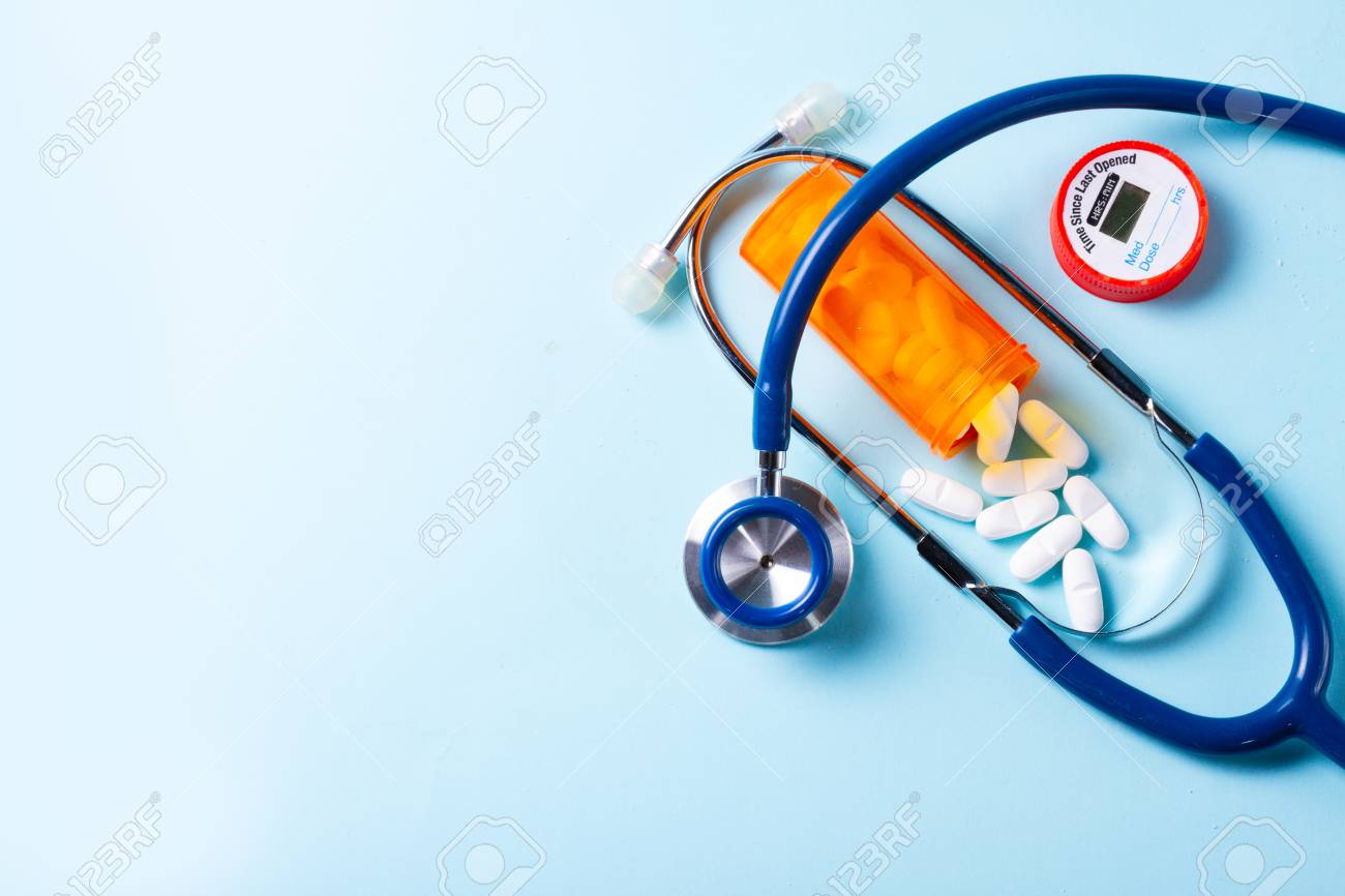 White pills in orange bottle with stethoscope on blue with copy space - 111498491 White pills in orange bottle with stethoscope on blue with copy space - 111498491