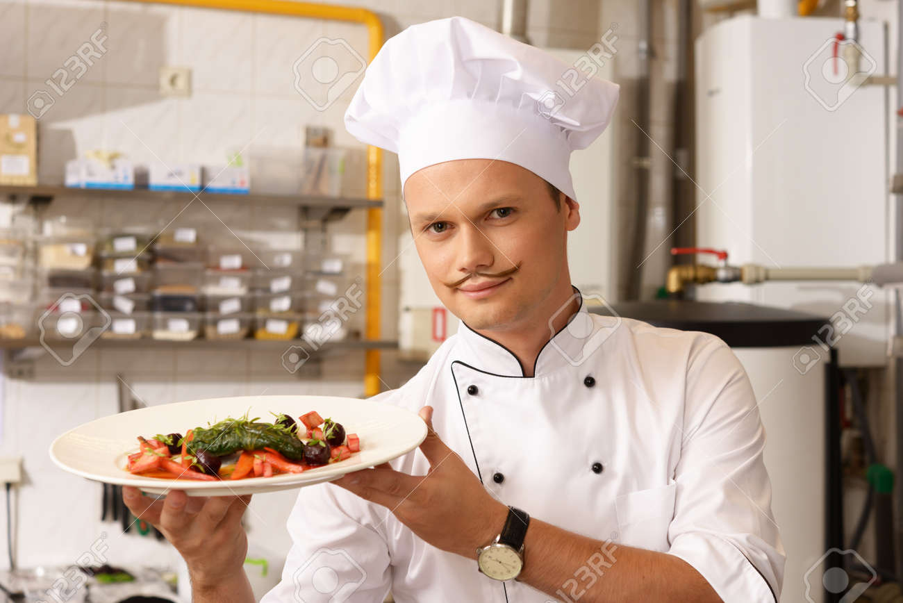 young chief cook with gourmet food on kitchen in restaurant stock