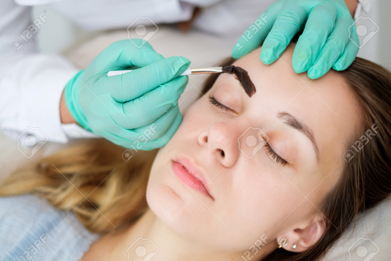 Beautician performing henna brows correction - 125680795 Beautician performing henna brows correction - 125680795