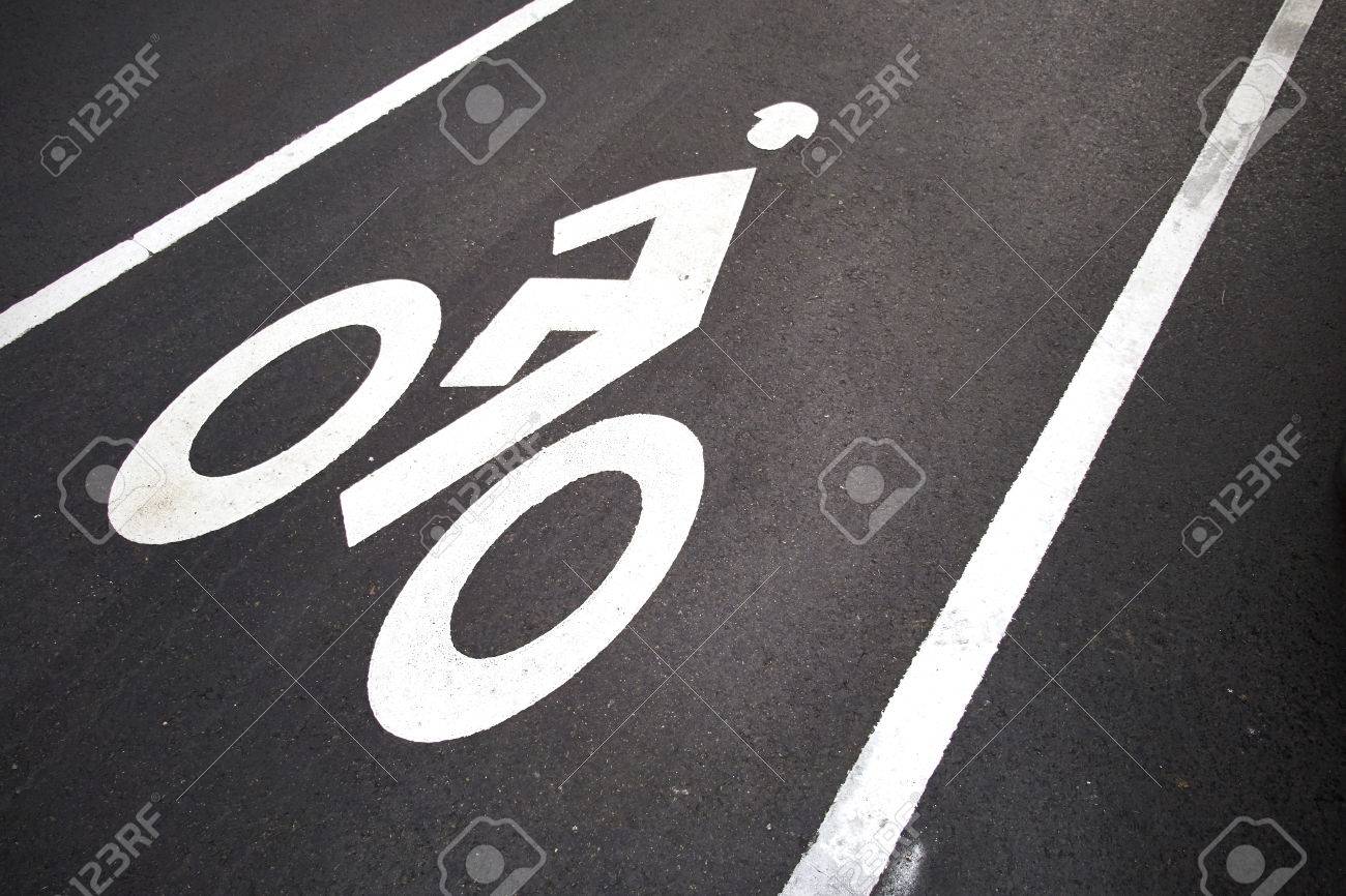 Bicycle lane. White mark of bicycle and white arrow pointing one way on asphalt path - 24858453 Bicycle lane. White mark of bicycle and white arrow pointing one way on asphalt path - 24858453