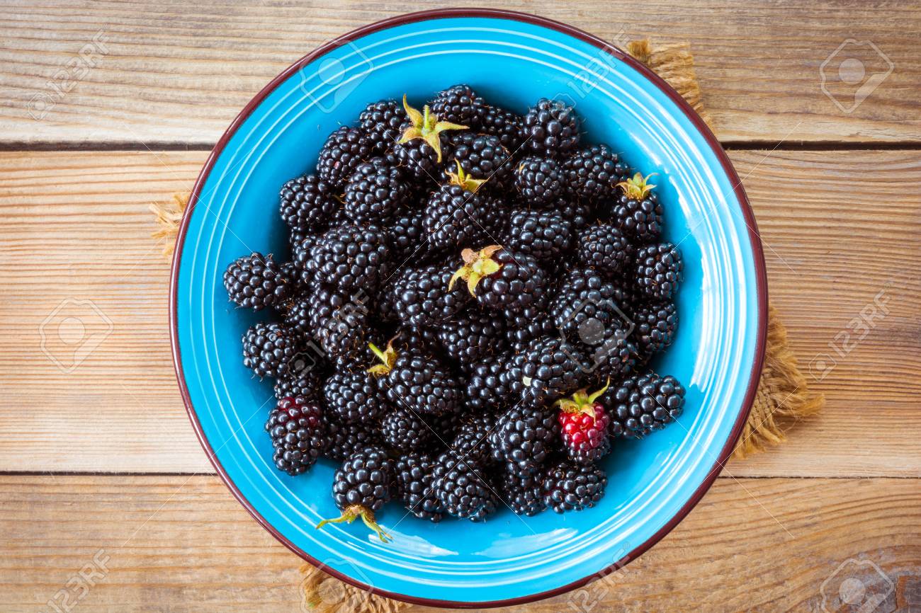 Fresh blackberries in blue ceramic bowl on wooden background in rustic style. Top view. - 61472572 Fresh blackberries in blue ceramic bowl on wooden background in rustic style. Top view. - 61472572