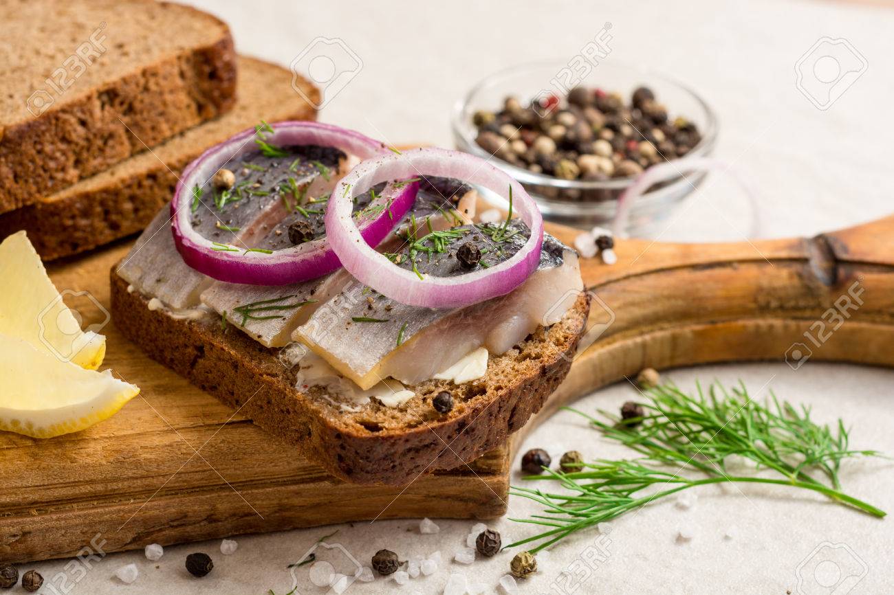 Sandwich with salted herring, butter and red onion on old rustic cutting board. Selective focus. - 79116976 Sandwich with salted herring, butter and red onion on old rustic cutting board. Selective focus. - 79116976