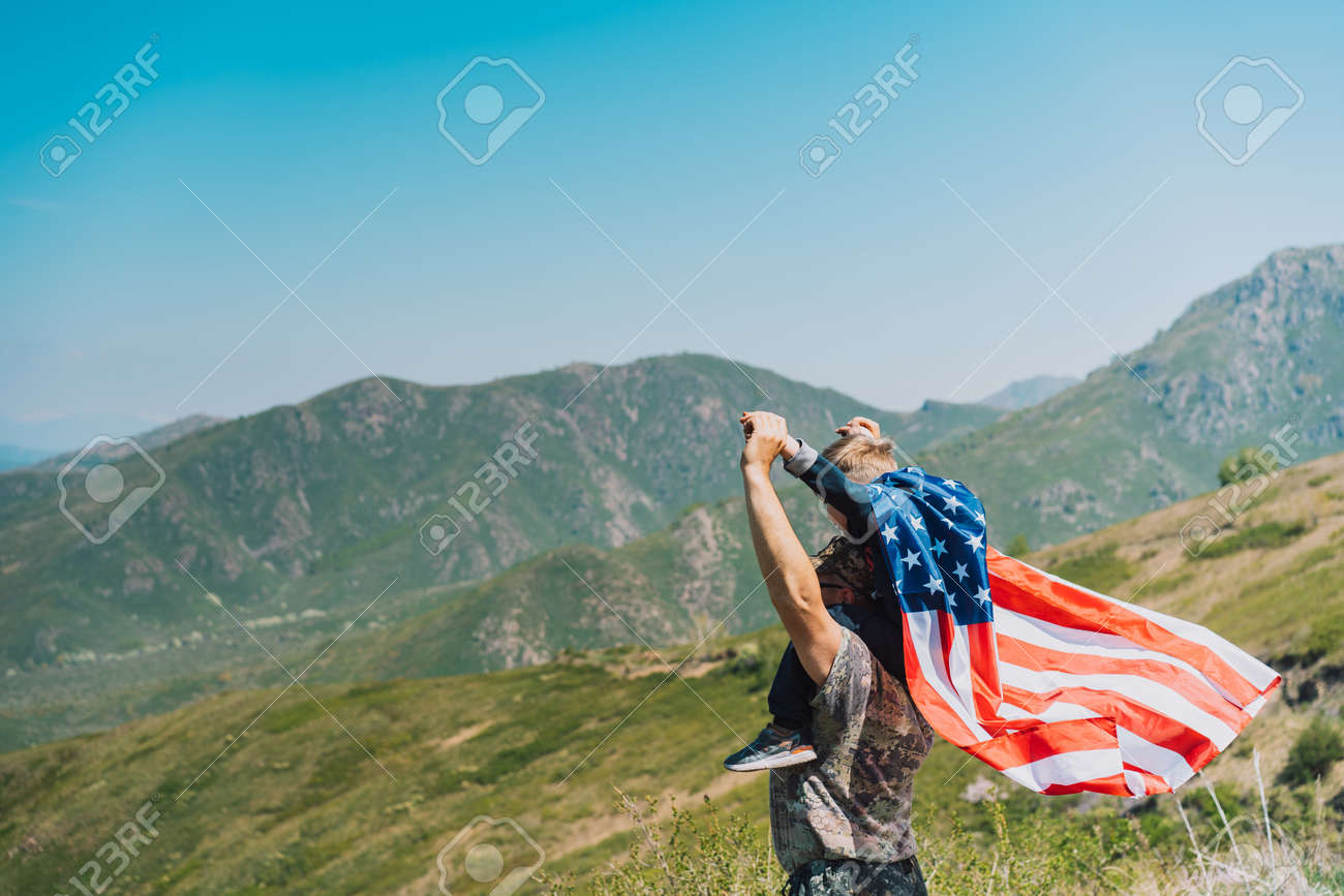 Man and child celebrate fourth of july with american flag in nature. - 169694085 Man and child celebrate fourth of july with american flag in nature. - 169694085
