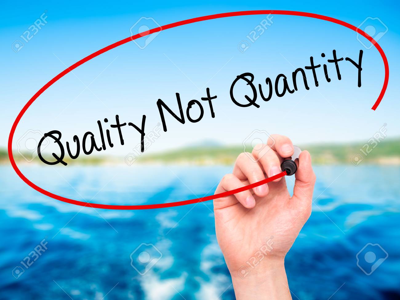 man hand writing quality not quantity with black marker on visual screen isolated on nature