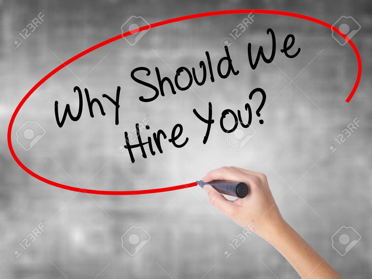 man hand writing why should we hire you with black marker on