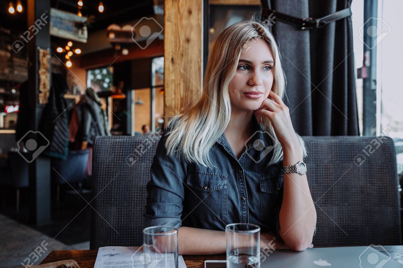 beautiful young woman sitting at table with laptop and looking at window in cafe - 97933691 beautiful young woman sitting at table with laptop and looking at window in cafe - 97933691