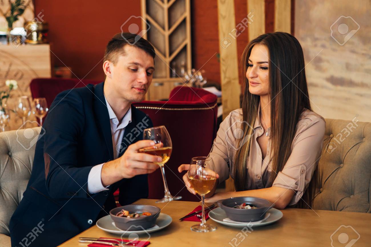 smiling couple having dinner and drinking white wine at date in restaurant - 97567513 smiling couple having dinner and drinking white wine at date in restaurant - 97567513