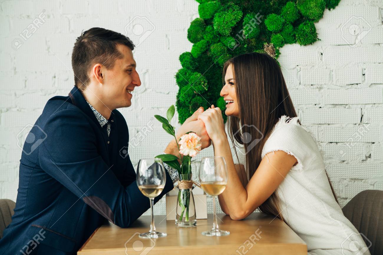 Cheerful young man and woman are dating in restaurant. They are sitting at the table and looking at each other with love. - 97567498 Cheerful young man and woman are dating in restaurant. They are sitting at the table and looking at each other with love. - 97567498