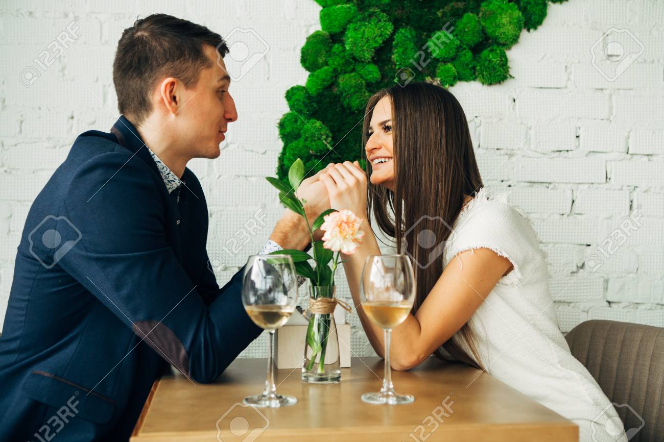 Cheerful young man and woman are dating in restaurant. They are sitting at the table and looking at each other with love. - 97567499 Cheerful young man and woman are dating in restaurant. They are sitting at the table and looking at each other with love. - 97567499