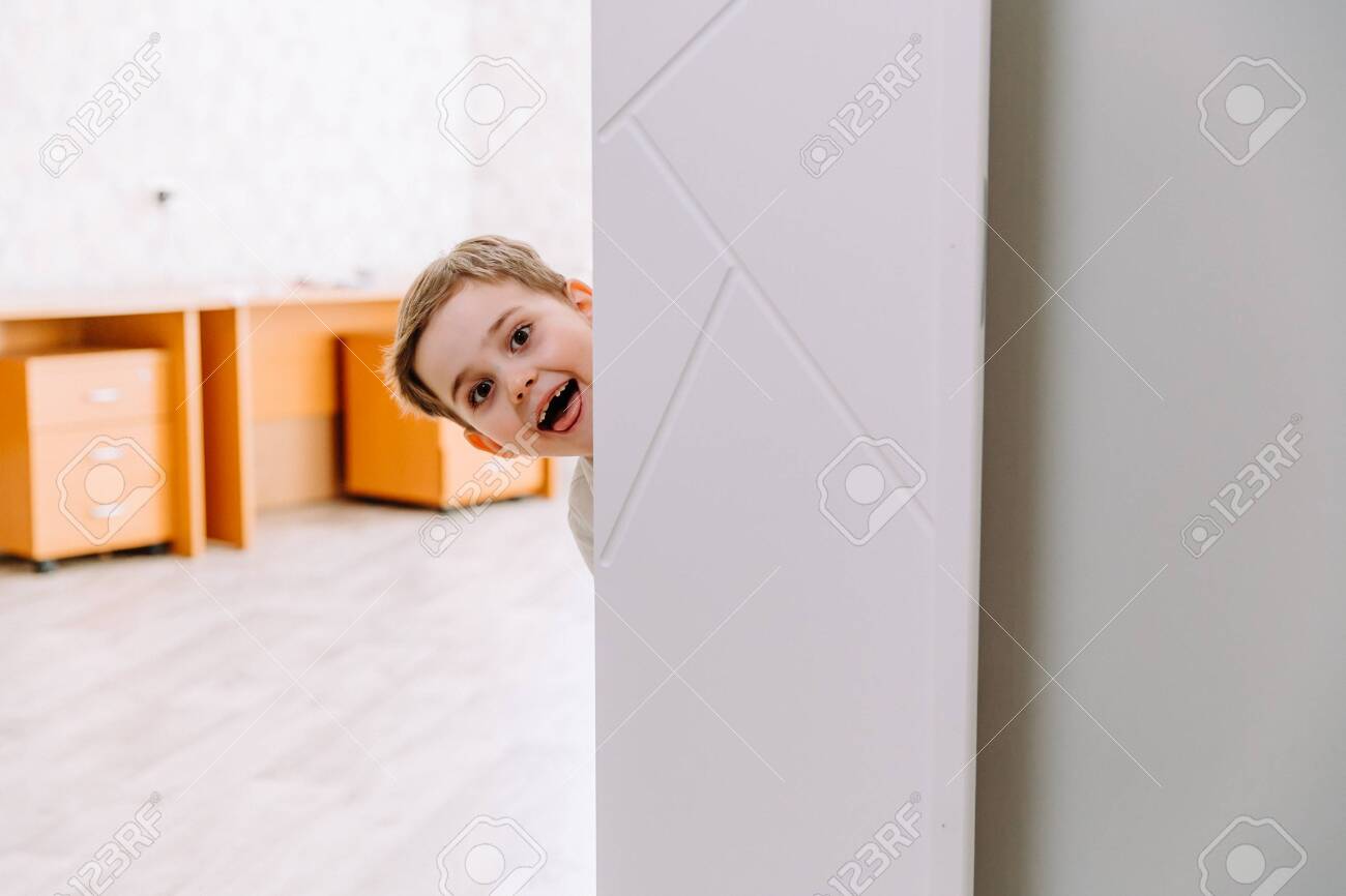 the boy peeks playfully around the corner - 145783956 the boy peeks playfully around the corner - 145783956