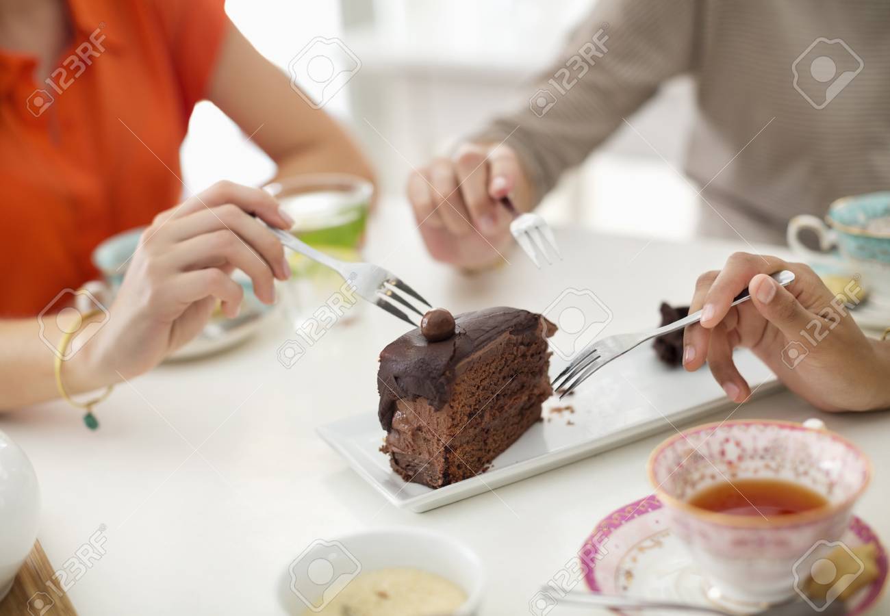 stock photo women sharing slice of cake