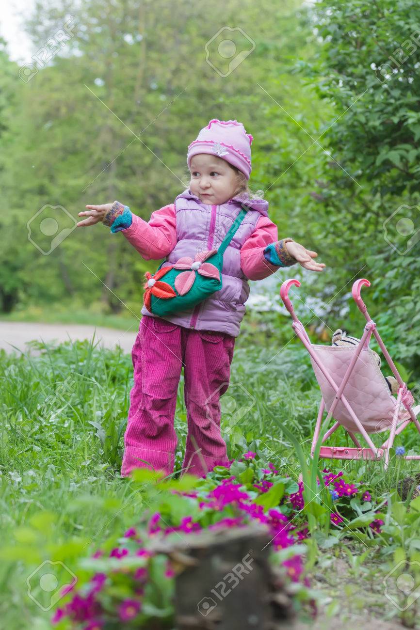 little girl with pink toy stroller is making helpless shrug gesture
