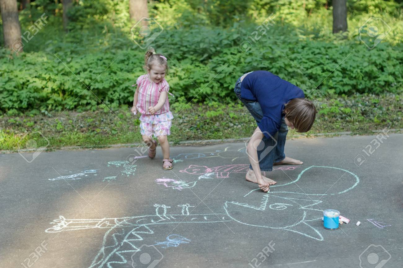 Sibling children are having fun during sidewalk chalking on asphalt surface - 58134494 Sibling children are having fun during sidewalk chalking on asphalt surface - 58134494