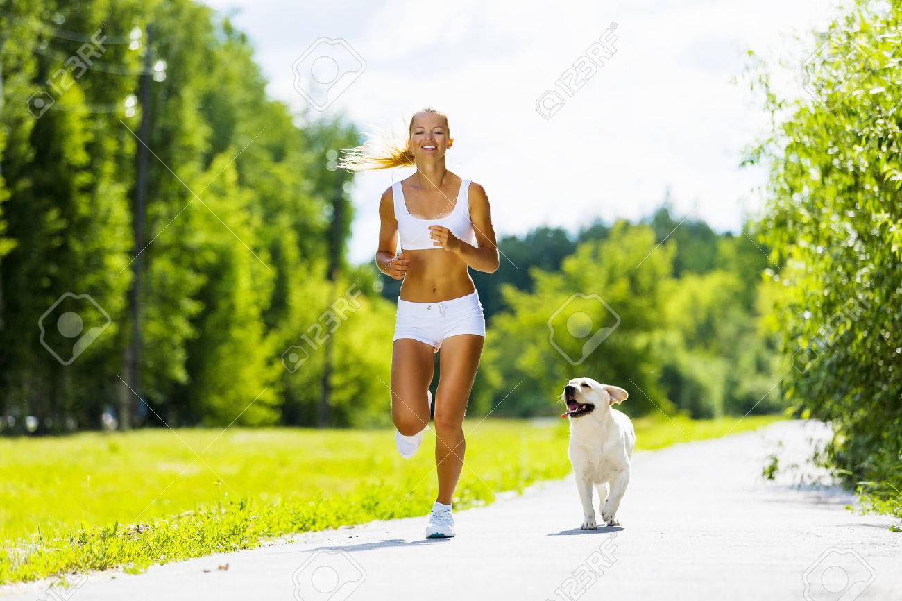 young attractive sport girl running with dog in park stock photo