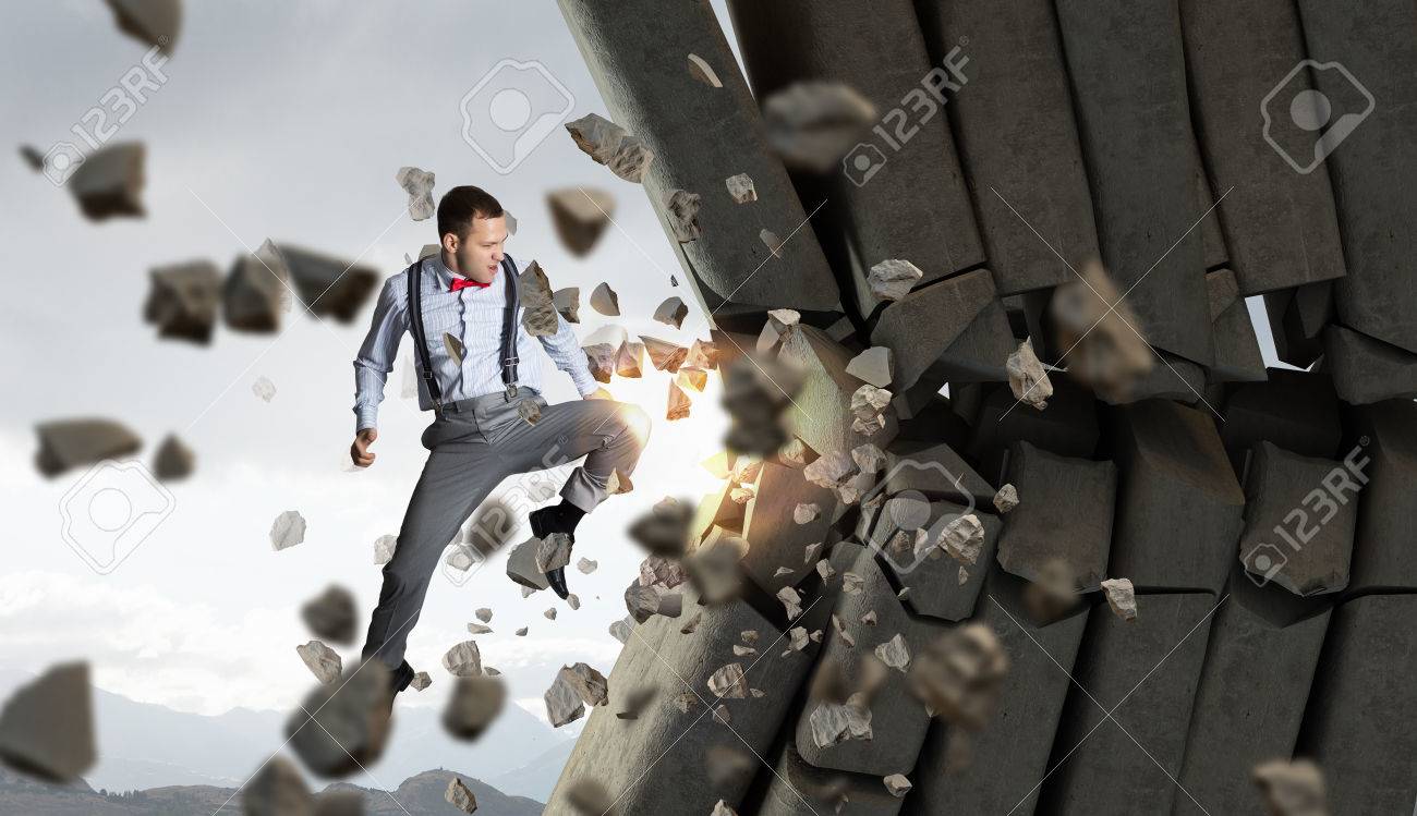 determined businessman breaking stone bricks with hand punch stock