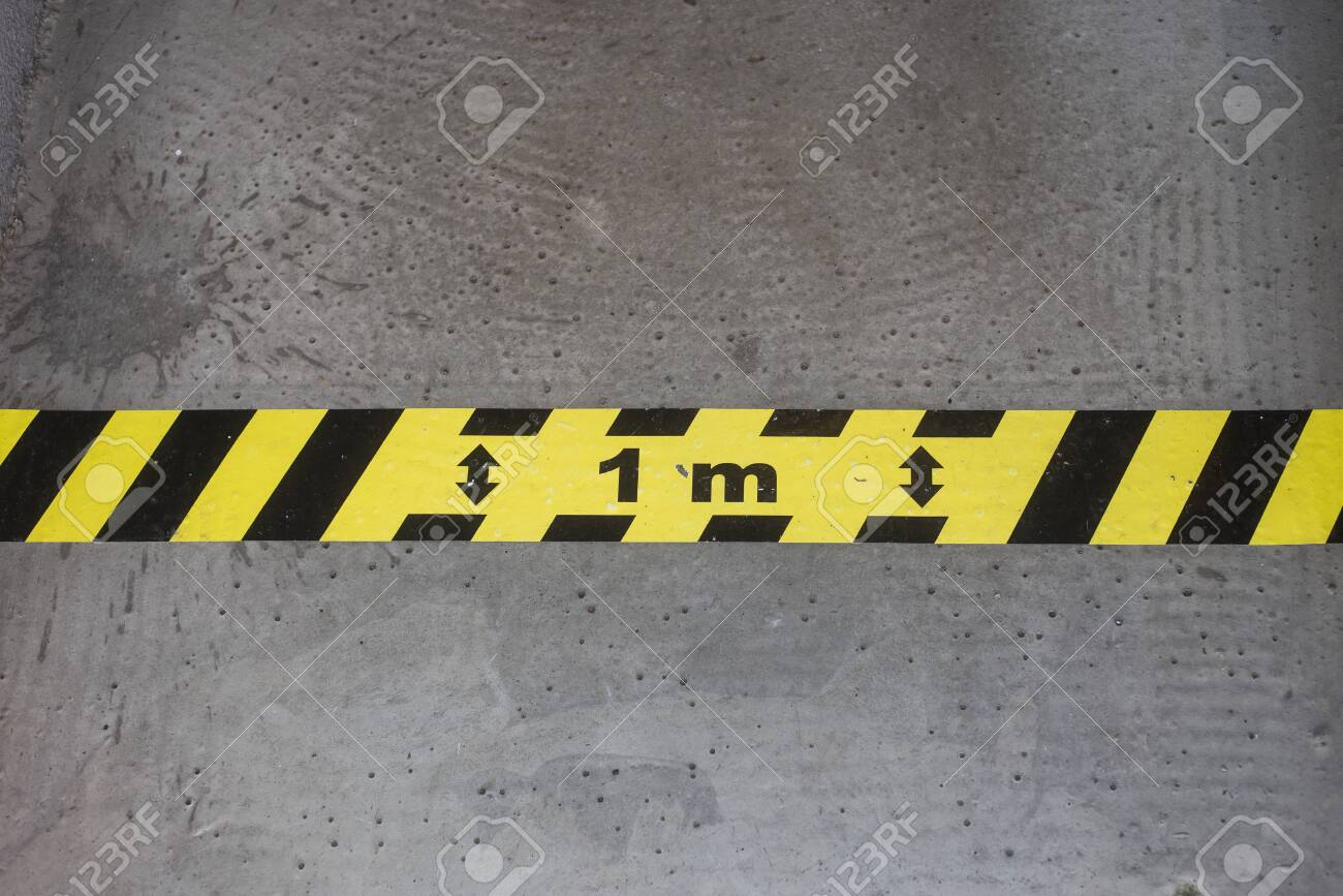 Closeup of yellow and black stripped line on the floor - Social distancing line - 149980103 Closeup of yellow and black stripped line on the floor - Social distancing line - 149980103