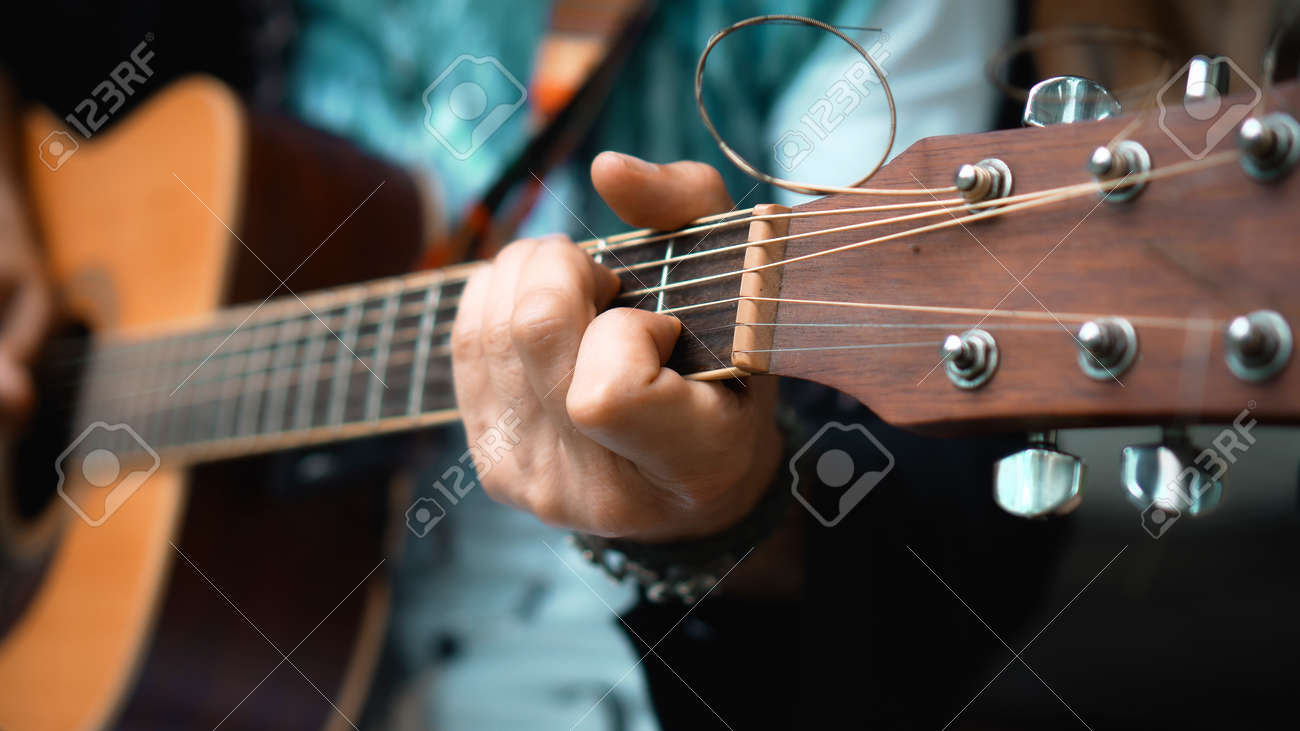 The young man plays hands and on a classic acoustic wooden guitar on the street using a microphone - 170790645 The young man plays hands and on a classic acoustic wooden guitar on the street using a microphone - 170790645