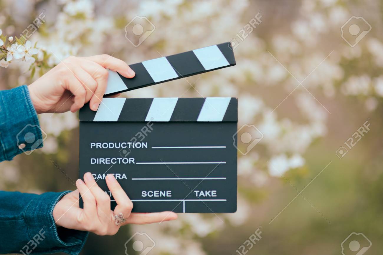 Hands Holding Film Slate Cinema Clapper on Spring Blooming Background - 94389939 Hands Holding Film Slate Cinema Clapper on Spring Blooming Background - 94389939