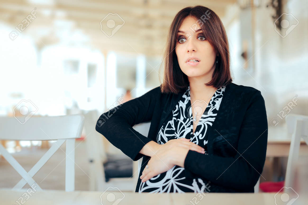 Worried Pregnant Woman Feeling her Belly in a Restaurant - 171415171 Worried Pregnant Woman Feeling her Belly in a Restaurant - 171415171