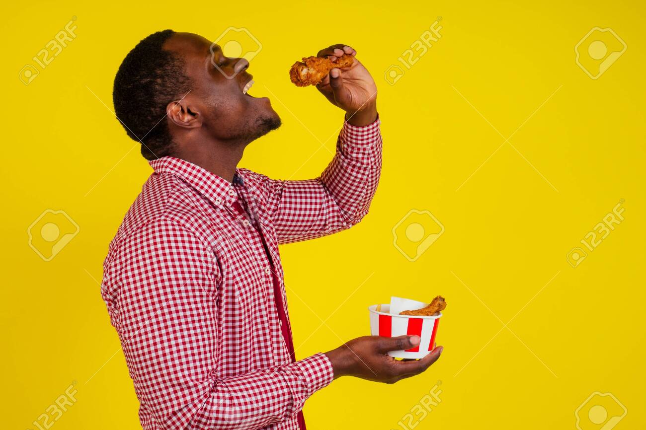 Funny African American Man Eating Fried Chicken Leg In Studio Yellow  Background. Stock Photo, Picture and Royalty Free Image. Image 132706663., image size:1300x866