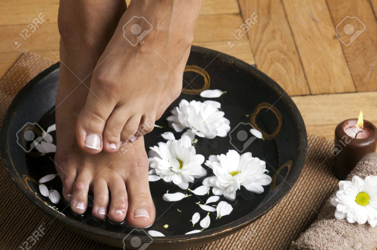 feminine feet in foot spa bowl with flowers towel and candle foto