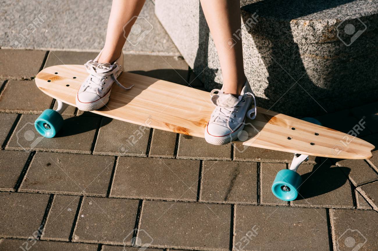 休憩後 極端な面白い彼女の木製ロング スケート ボードに乗る白いスニーカーの女性足のクローズ アップ モダンな都市内気な少女は 楽しい時を過します スケート ボードの良い日当たりの良い夏の日と 楽しい時を過します の写真素材 画像素材 Image