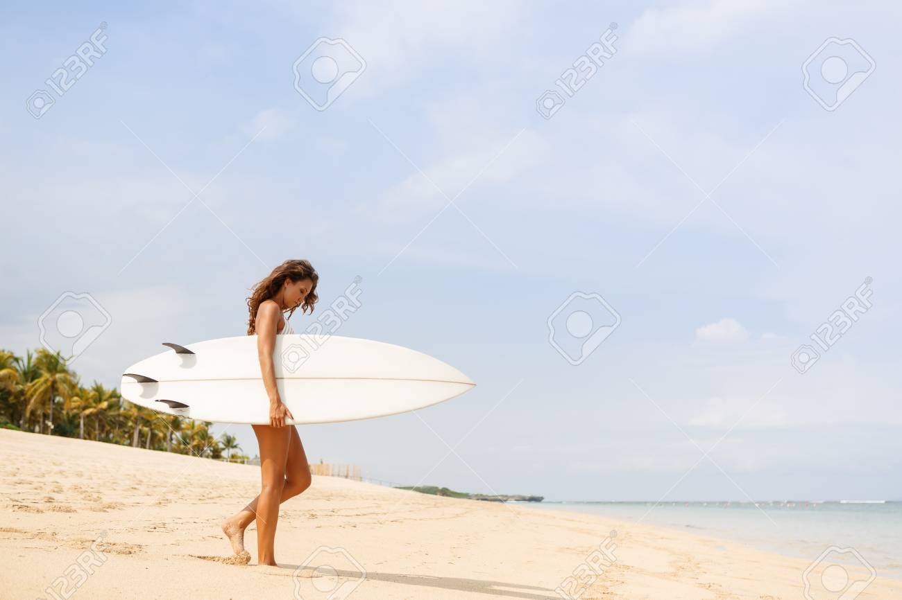 日の出や日没で白いサーフィン ショート ボード サーフボード空白ボードでセクシーなビキニ水着の女の子をサーフィン砂浜散歩に海へきれいに密着 休暇の概念 夏の休日 観光 スポーツ の写真素材 画像素材 Image