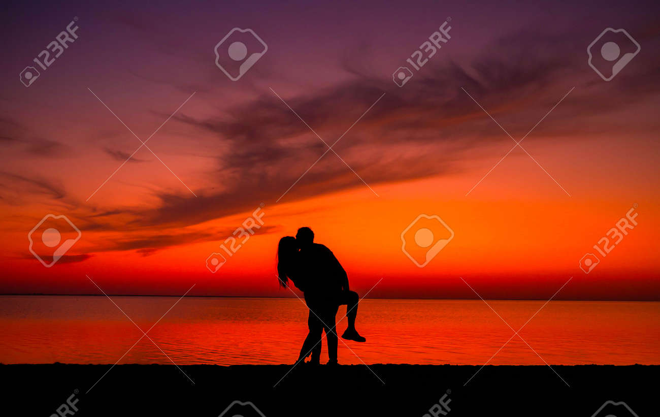恋人のロマンチックなカップルのシルエットは、背景にカラフルな夕日を  