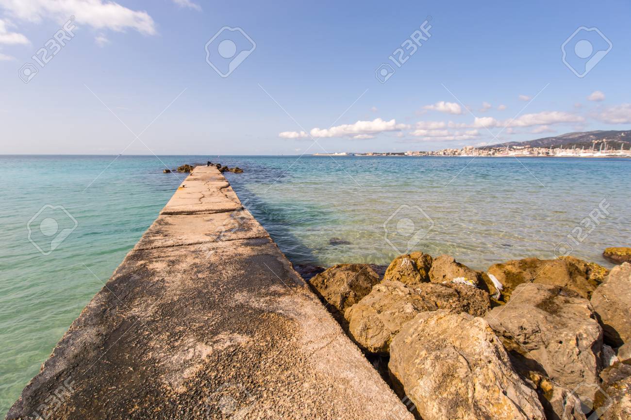 Long Pier And Crystal Clear Water Of The Palma De Mallorca Seacost
