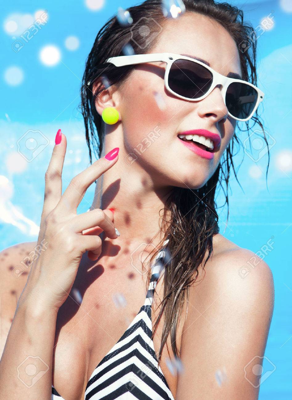 Colorful summer portrait of young attractive happy brunette woman wearing sunglasses at the swimming pool - 30302521 Colorful summer portrait of young attractive happy brunette woman wearing sunglasses at the swimming pool - 30302521