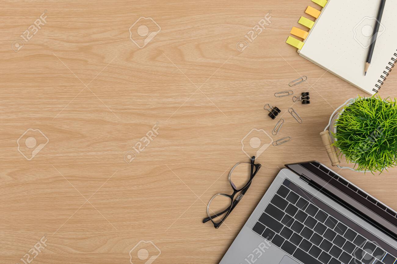 Top view Wood office desk table. Flat lay Workspace with eye glasses, tree pot, laptop, paper clip, clipboard, notebook, pencil, sticky note office supplies on wooden background - 148080903 Top view Wood office desk table. Flat lay Workspace with eye glasses, tree pot, laptop, paper clip, clipboard, notebook, pencil, sticky note office supplies on wooden background - 148080903