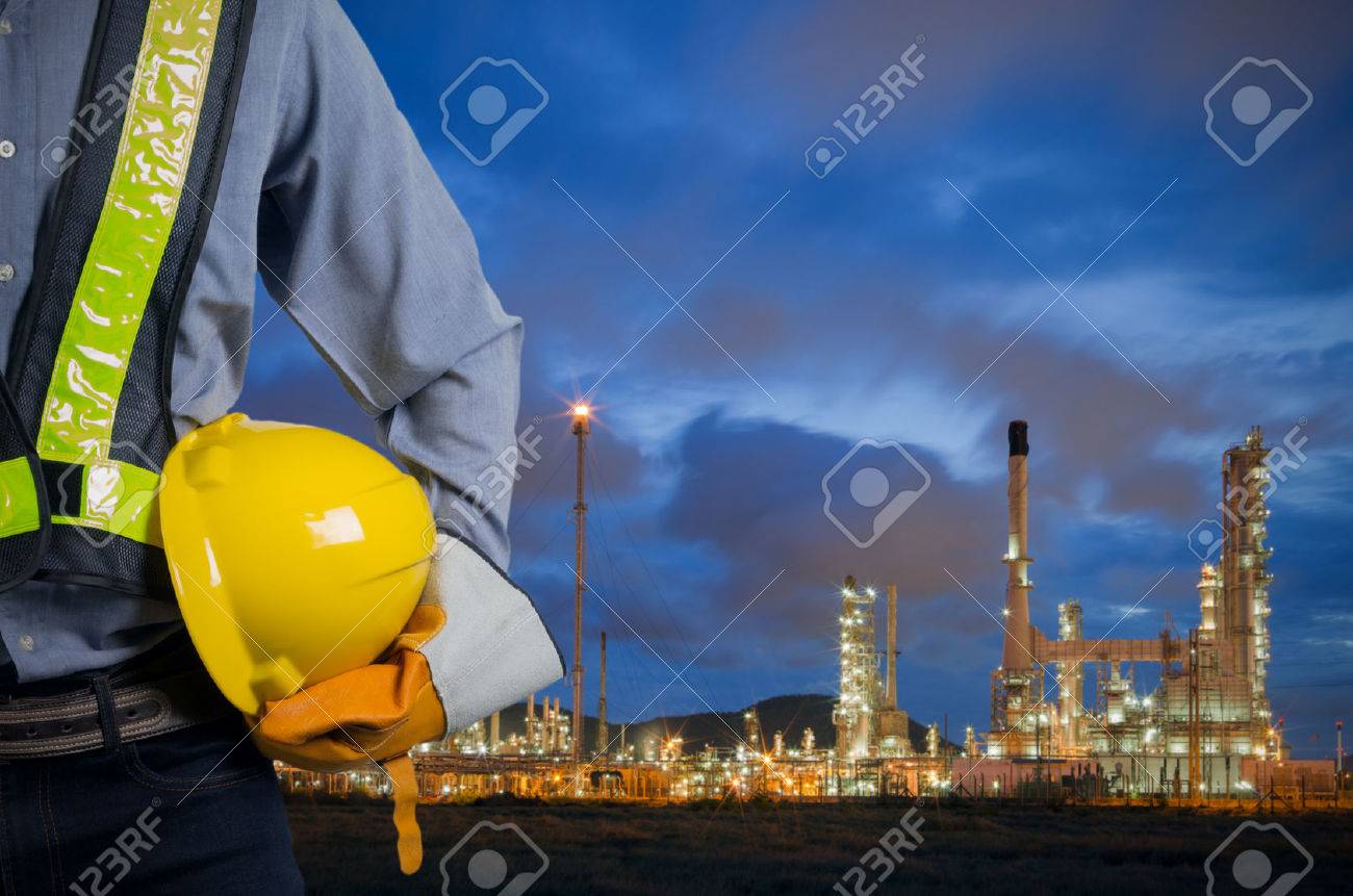 Engineer holding a yellow helmet for the safety of workers on the background oil refinery. Beautiful sky at dawn - 51644295 Engineer holding a yellow helmet for the safety of workers on the background oil refinery. Beautiful sky at dawn - 51644295