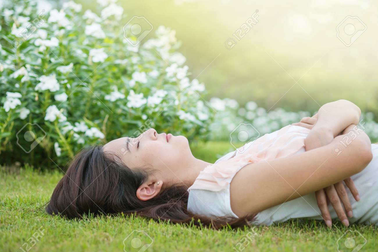 アジアの女性の横になっていると 彼女は午後に疲れて後草原で寝ています の写真素材 画像素材 Image